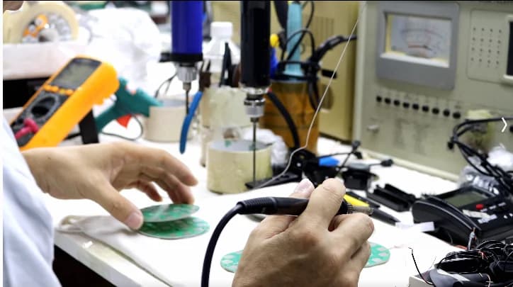 Technician soldering a telephone circuit board at CHEETA